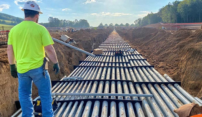 A construction worker overseeing a long run of perfectly aligned underground conduits.